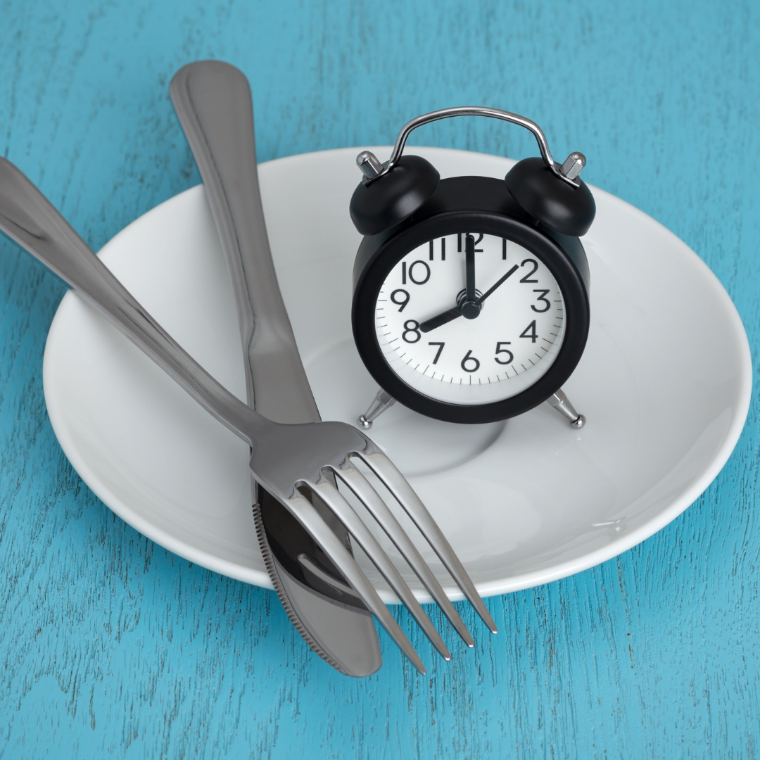 An empty plate with a fork and knife with a clock
