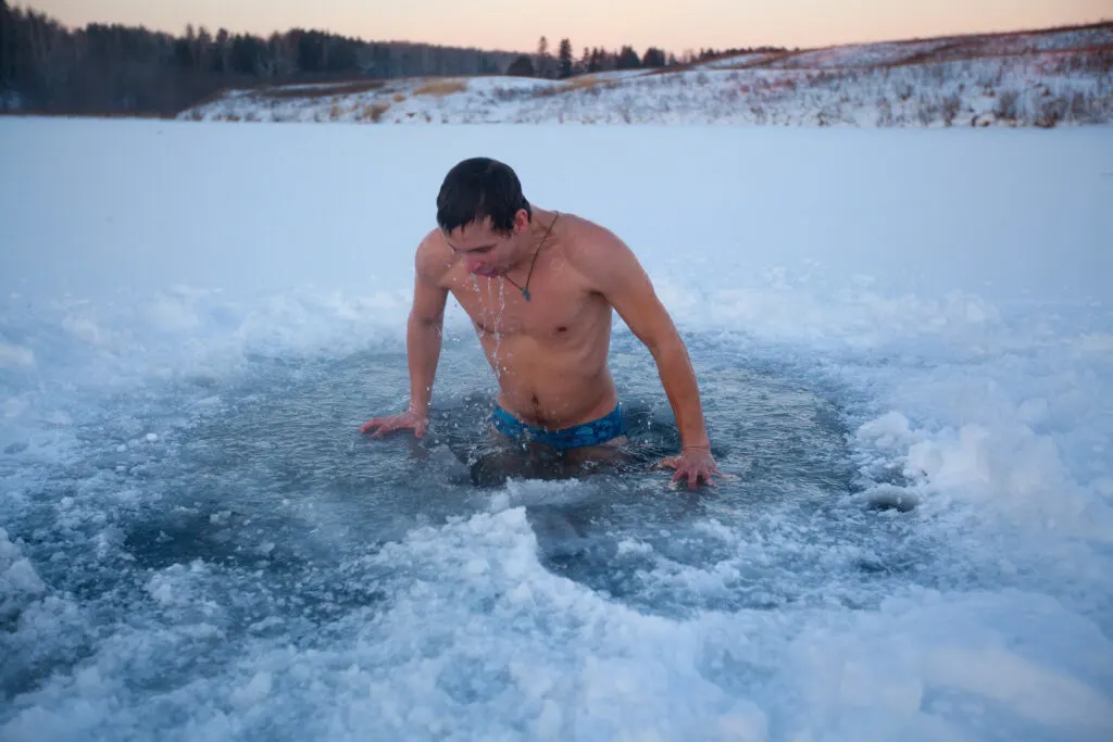 Young man having recreational swim in the ice hole