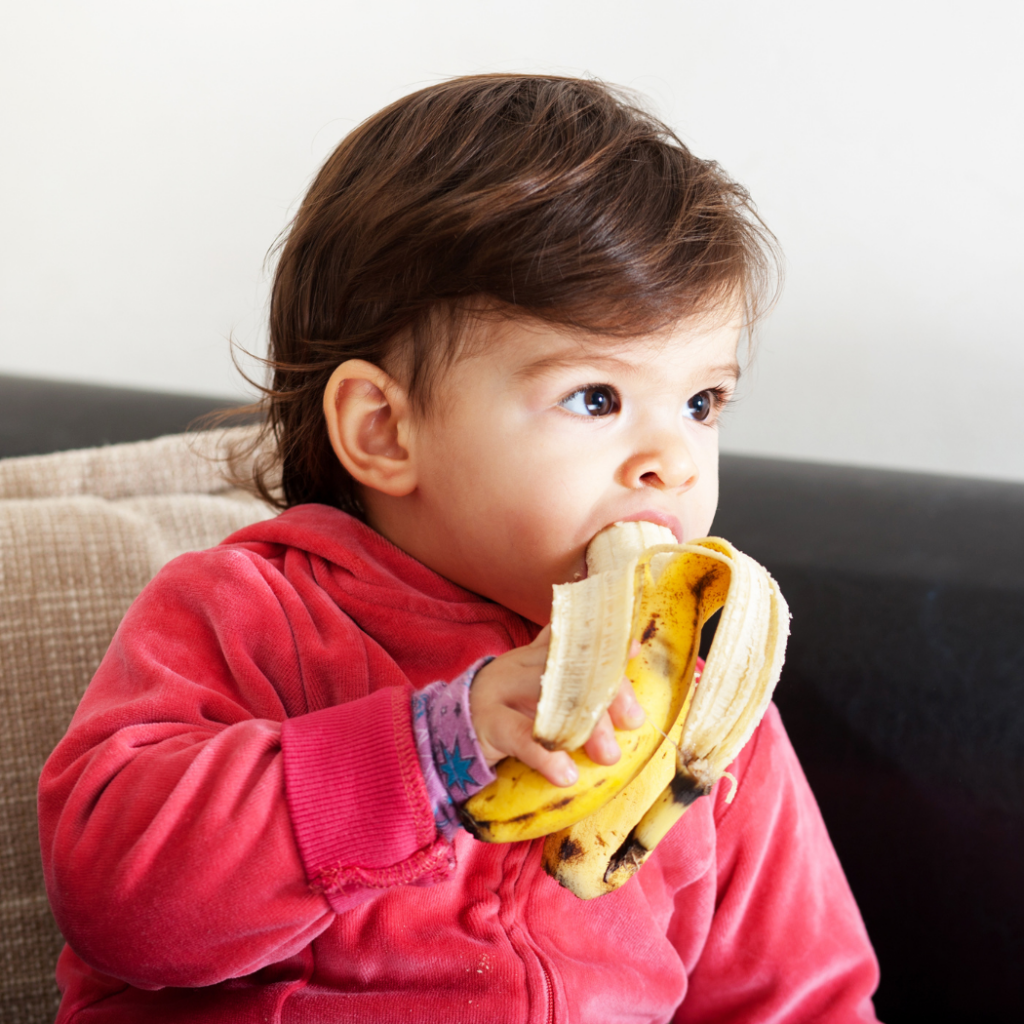 a little boy eating a potassium-rich food, a banana