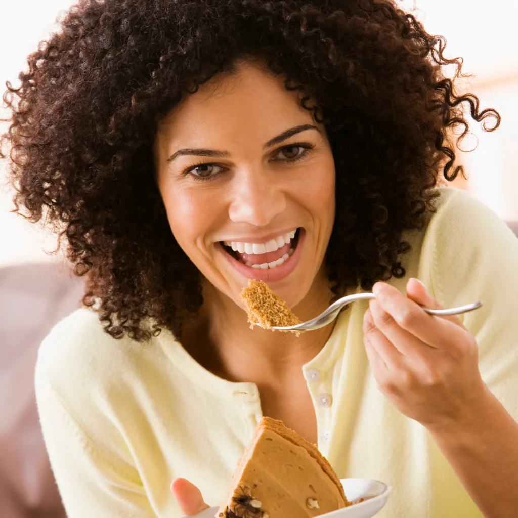 A woman happily eating pie - How to Handle Cravings When Detoxing