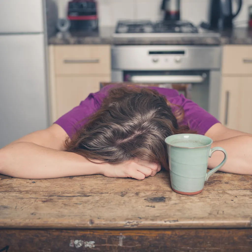 a woman tired from sugar detoxing with her head on the table
