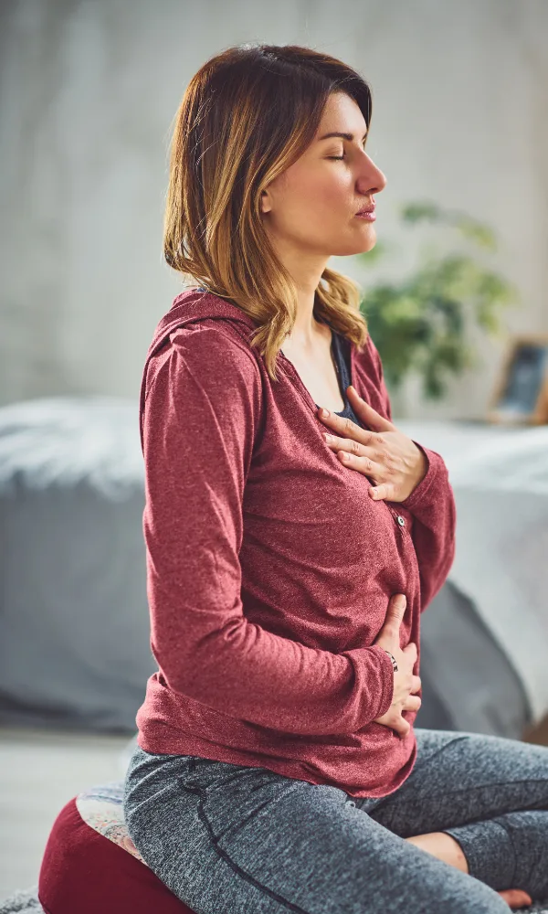 a woman sitting on a pillow breathing and meditating