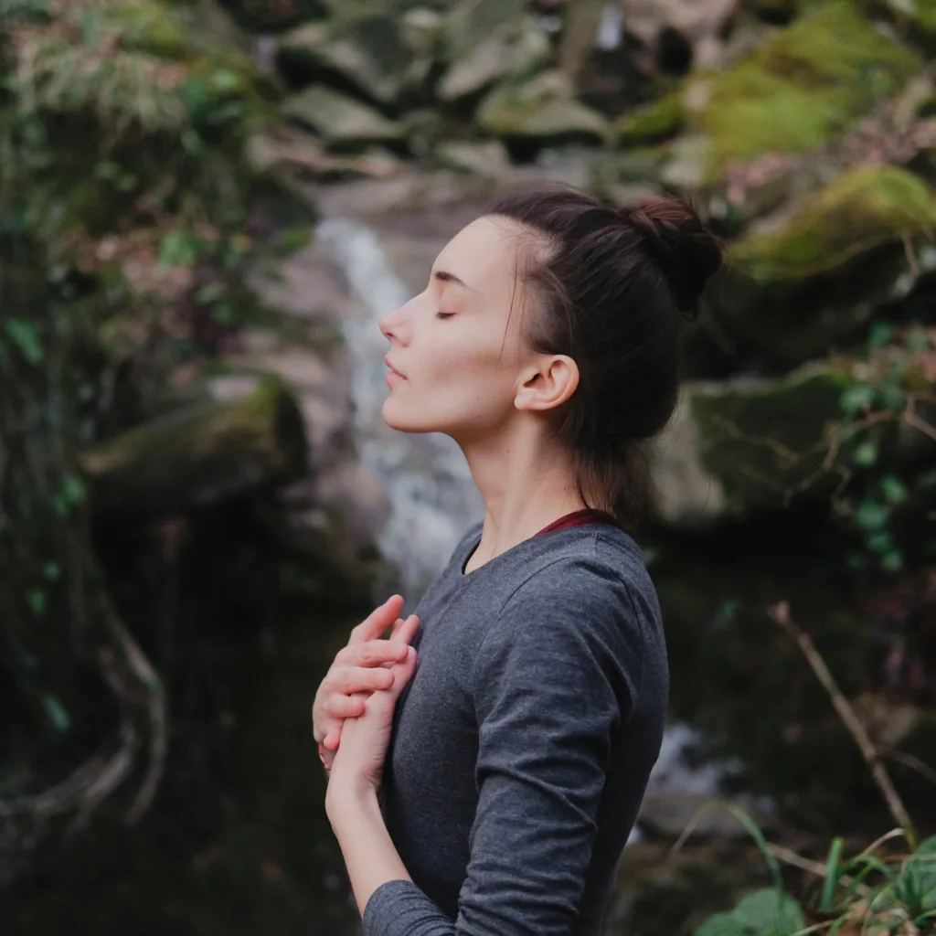 a woman sitting with her eyes closed outside meditating